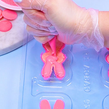 sealing chocolate bunny with melted pink chocolate